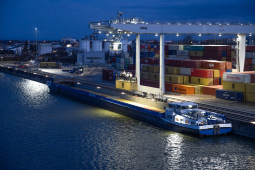 Verladung von Containern in ein Binnenschiff bei Nacht